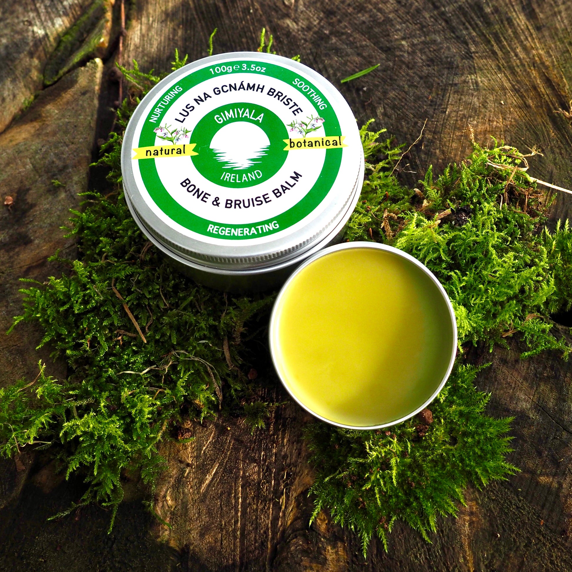 Balm container with green lid and white body on a wooden surface with moss